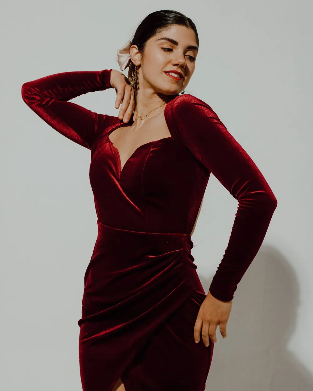 A bordeaux velvet dress with a softly sculpted shoulder